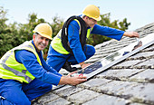 Workers installing solar panels on roof
