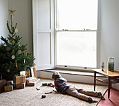 Boy playing with train by Christmas tree