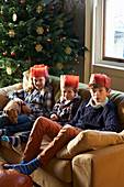 Children in paper crowns sitting on sofa