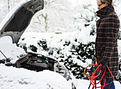 Woman working on broken down car in snow