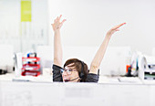 Businesswoman in headset cheering at desk