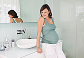 Pregnant woman leaning on bathroom sink