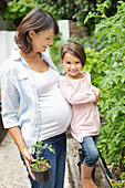 Girl and pregnant mother gardening