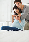 Man hugging pregnant girlfriend on bed