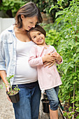 Pregnant mother and daughter gardening