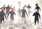 Triathletes in wetsuits running