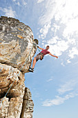 Climber scaling steep rock face