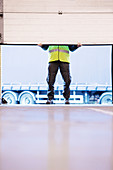 Worker lifting door in warehouse