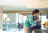 Mother hugging son in kitchen