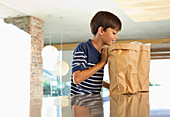 Boy looking through paper bag in kitchen