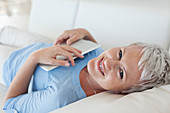 Woman holding tablet computer on sofa