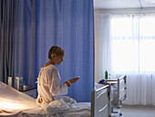 Patient using cell phone in hospital bed