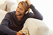 Man listening to headphones on sofa