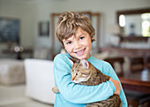 Boy hugging cat in living room