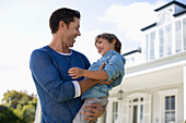 Father and son smiling outside house