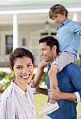 Family smiling outside house