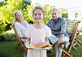 Girl holding plate of fruit outdoors