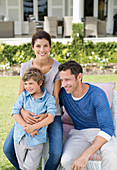 Family smiling outside house