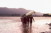 Rowing team carrying scull into lake