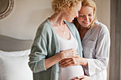 Mother holding pregnant daughter's belly