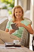 Smiling woman using tablet on porch