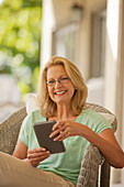 Smiling woman using tablet on porch