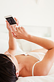 Woman laying in bed using cell phone