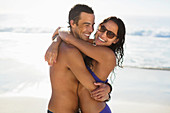 Portrait of happy couple hugging on beach