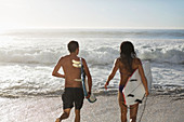 Couple running with surfboards