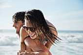 Man carrying enthusiastic woman on beach