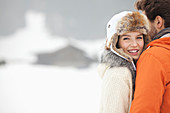 Smiling woman hugging man in snowy field