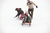 Family sledding in snowy field