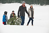 Smiling family dragging Christmas tree