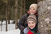 Happy boys leaning against tree
