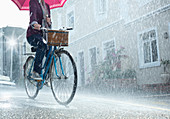 Woman riding bicycle with umbrella