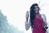 Smiling woman under umbrella in rain