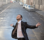 Happy businessman in rainy street