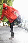 Man standing on one leg in rainy street