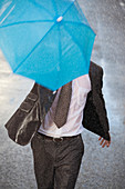 Businessman with tiny umbrella running