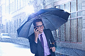 Happy businessman under umbrella