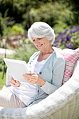 Senior woman using tablet in armchair