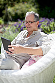 Senior man using tablet in armchair