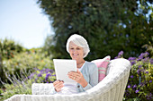 Senior woman using tablet in armchair