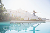 People practicing yoga at poolside