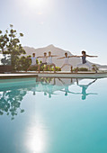 People practicing yoga at poolside