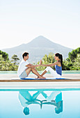 Couple practicing yoga poolside