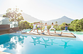 People practicing yoga at poolside