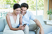 Couple using cell phone on sofa