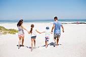 Family holding hands and walking on beach