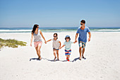 Family holding hands and walking on beach